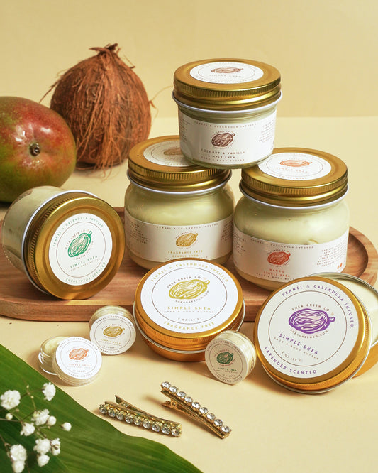 Jars of Simple Shea body butter with herbal infusion, displayed alongside natural ingredients like shea butter and fennel. The product is packaged in clear jars with labels and lids, some with fennel bulbs and leaves garnishing the area.