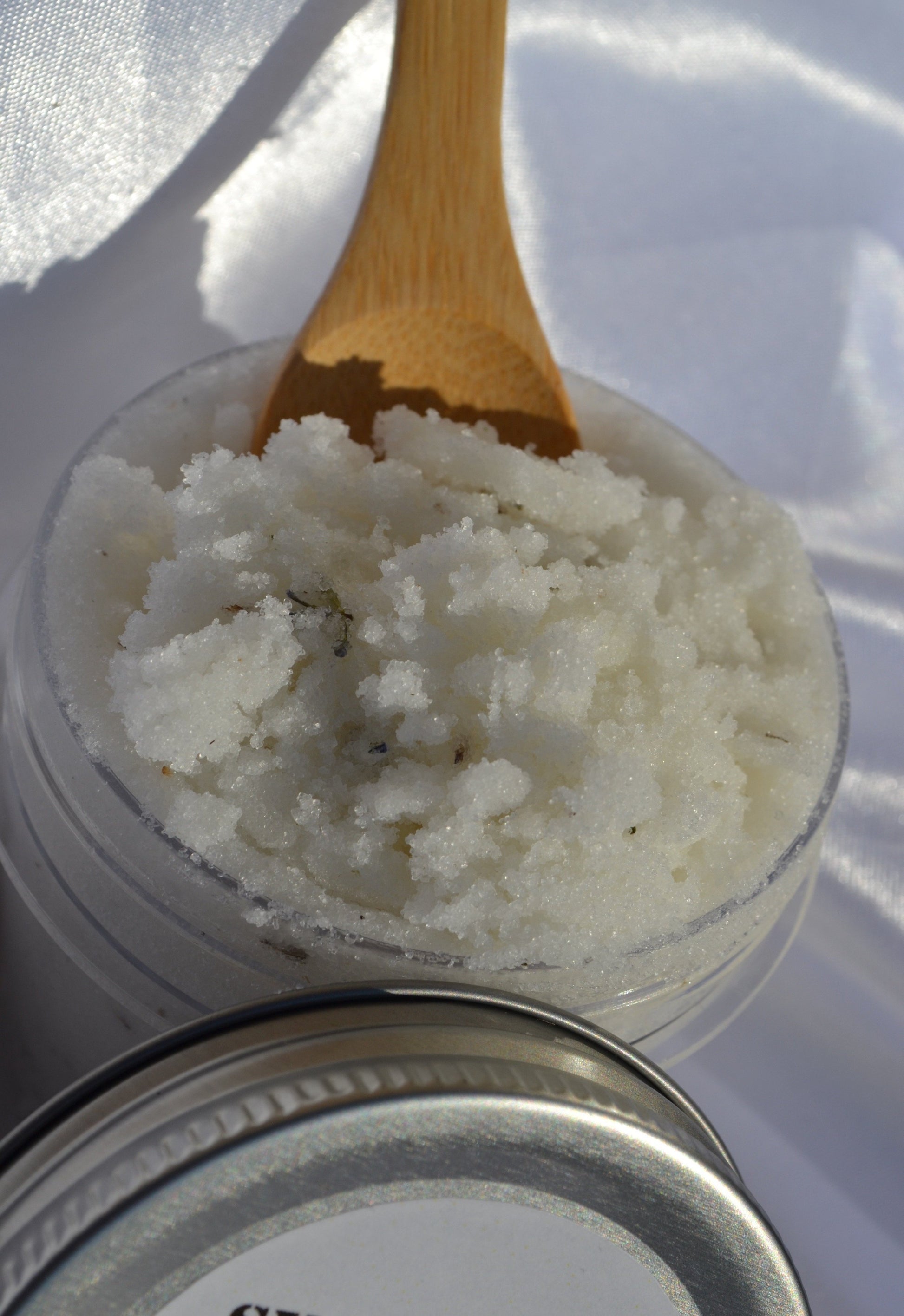 wooden spoon scooping cane sugar scrub with crushed lavender flakes